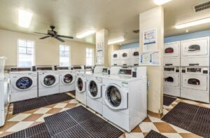laundry facilities, industrial washers and dryers, tile floor with mats on the ground windows inside facility