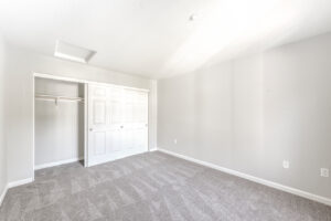 Unit Bedroom, new carpeting, white sliding closet doors, neutral toned walls, well lit from windows.