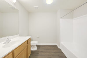 Unit Bathroom, wood like floors, bathtub/shower, light brown cabinetry, large vanity mirror, white countertop.