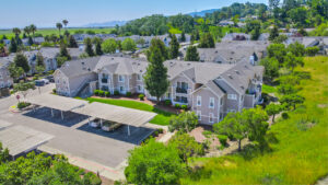 Aerial Exterior of bay vista at meadow park, trees scattered throughout the property, sprawling hills in the distance.